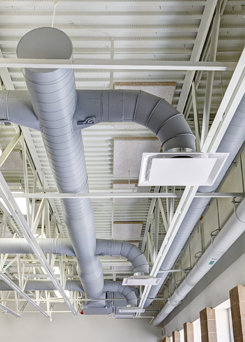 Exposed modern heating and cooling ductwork in the ceiling of a public school.